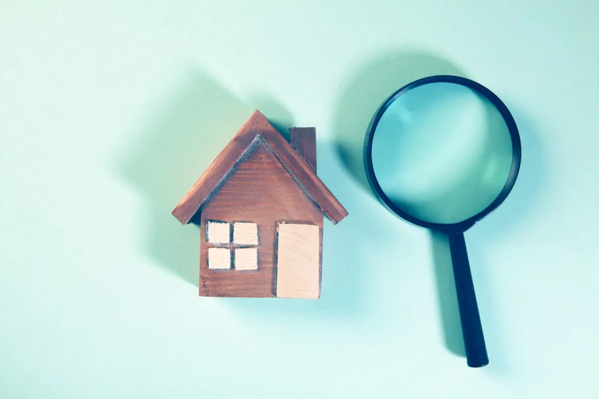 Magnifying glass examining a residential house model — representing the property inspection process in New Zealand