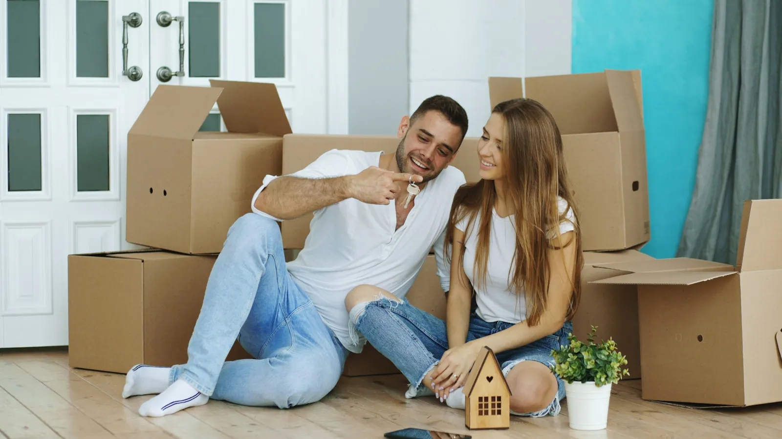 A first-home buyer couple standing outside their new New Zealand home holding the keys