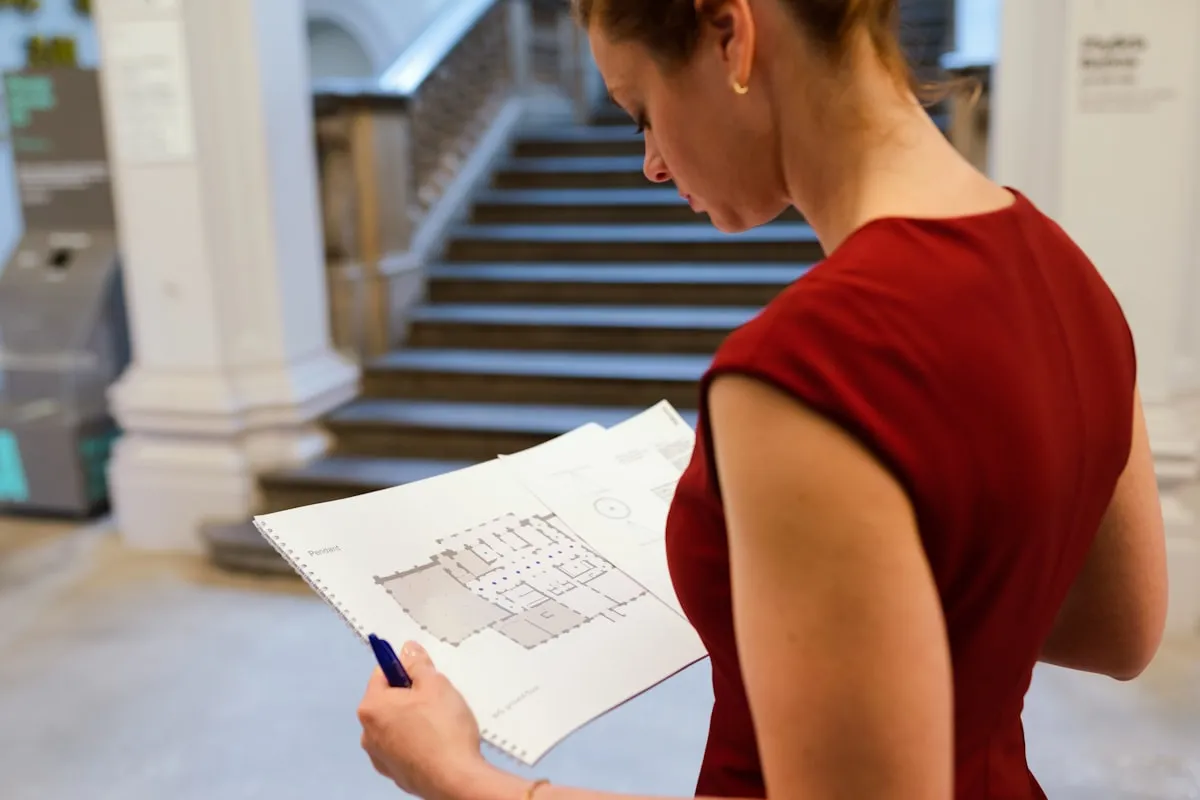 Woman reviewing a property floor plan document in a grand civic building — representing official council record review