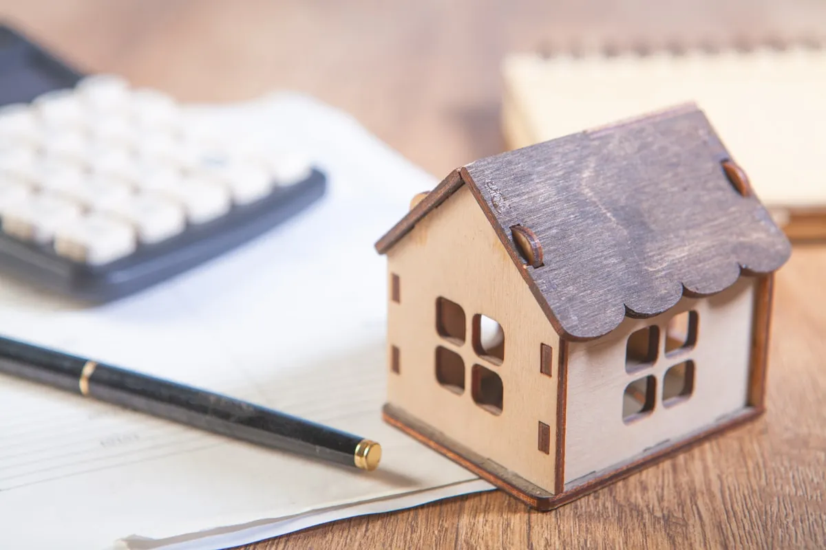 Property investment concept showing a house model with financial documents